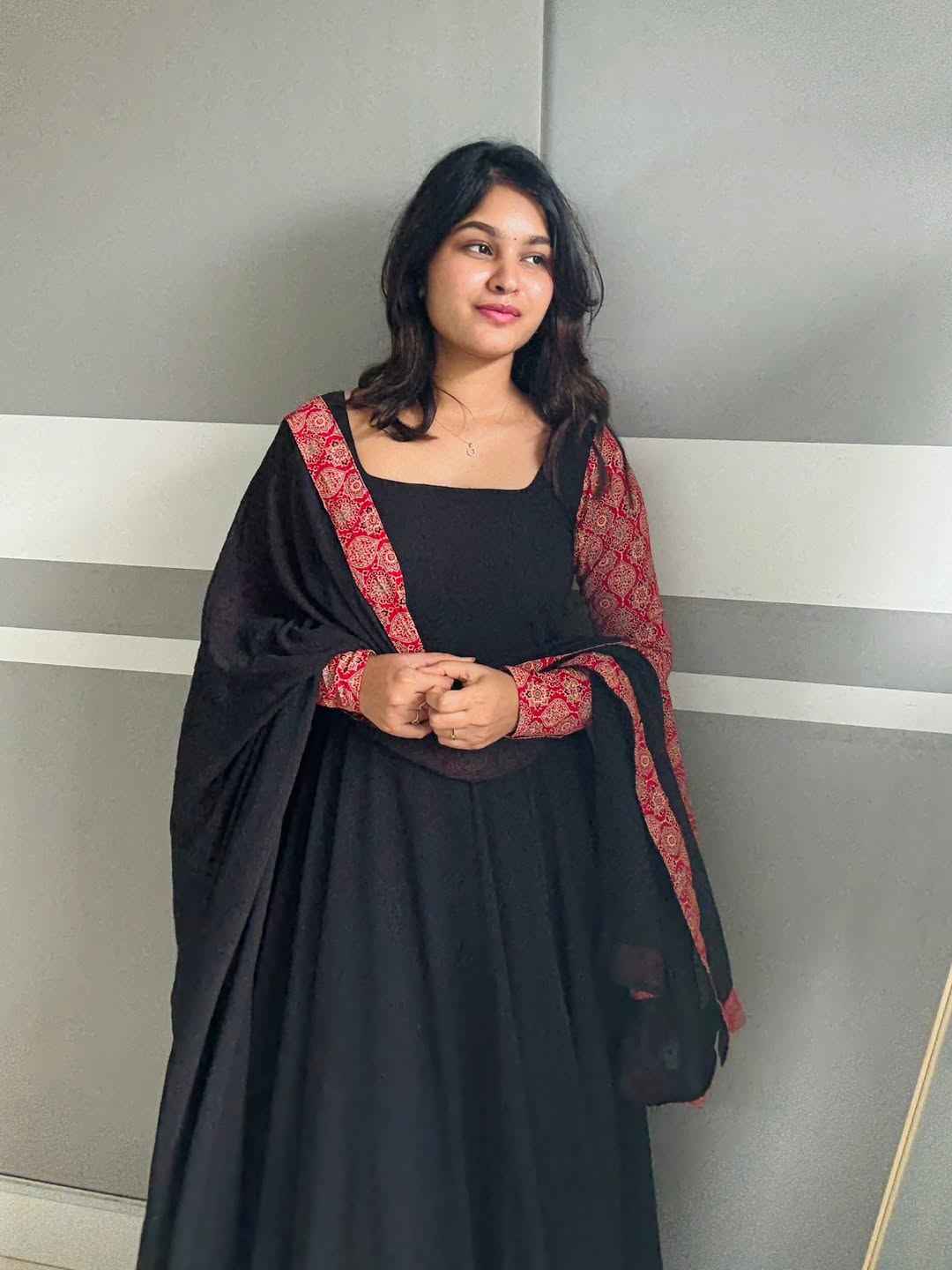 stunning portrait of a young woman exuding grace and poise in a traditional black Anarkali outfit.